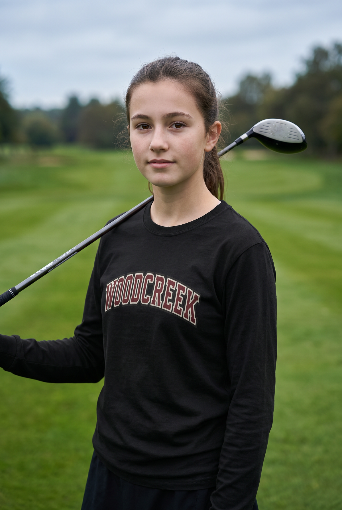 Woodcreek Girls Golf College Letter Long Sleeve Tee in Black, second view with a fairway wood on the shoulder