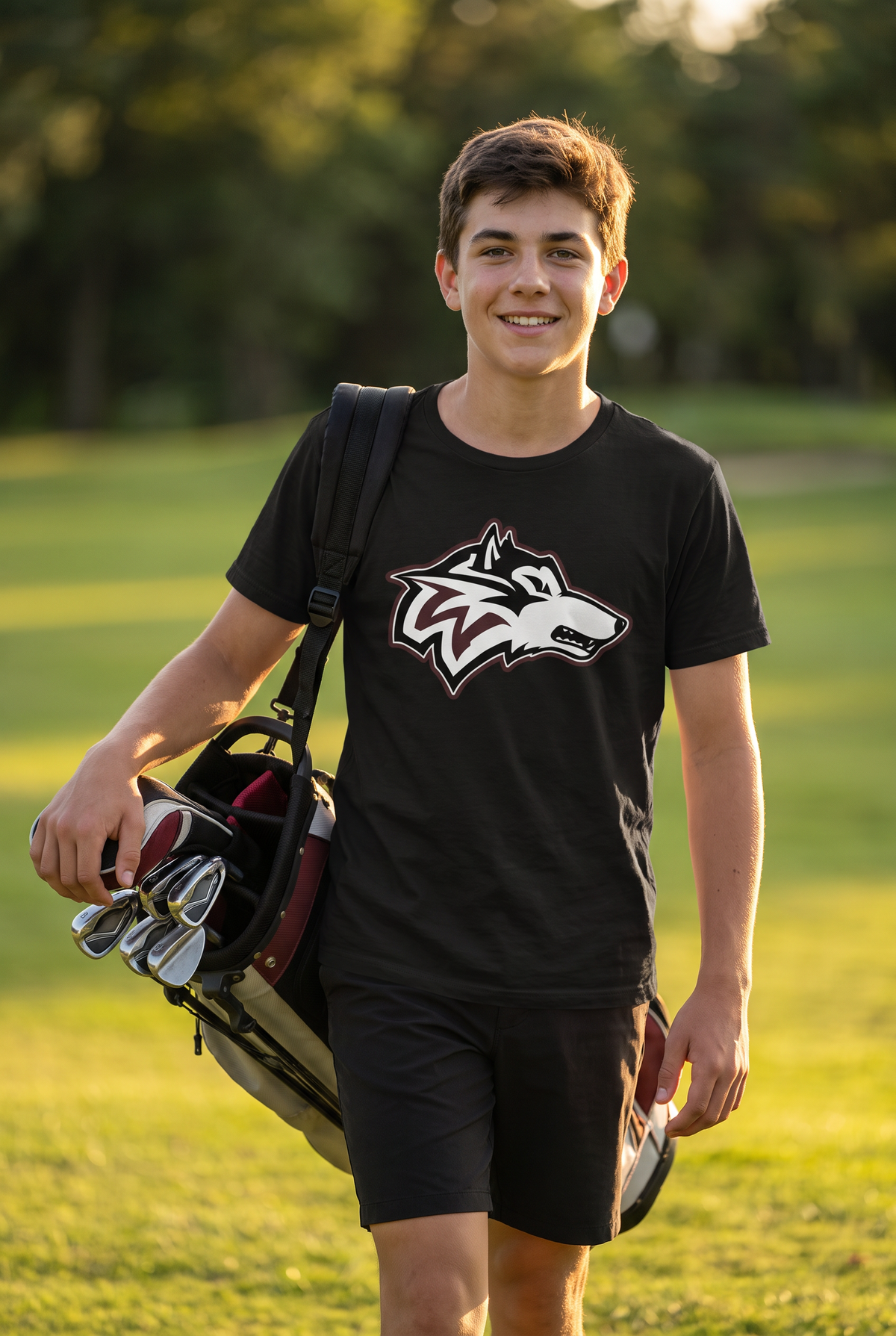 Woodcreek Boys Golf Value Tee in Black with the Woodcreek wolf head across the chest, worn walking the fairway