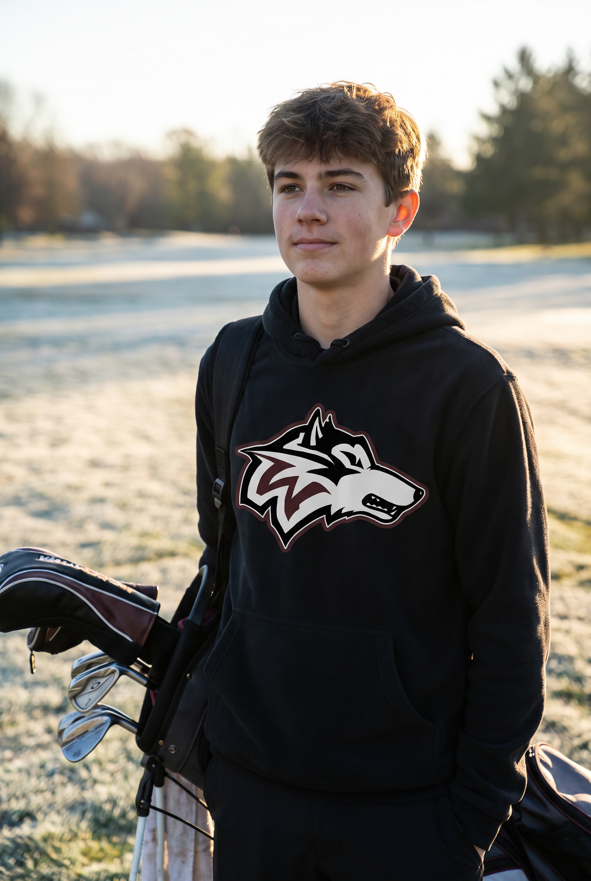 Woodcreek Boys Golf Fleece Hoodie in Black with the Woodcreek wolf head across the chest, worn on a frosty first tee