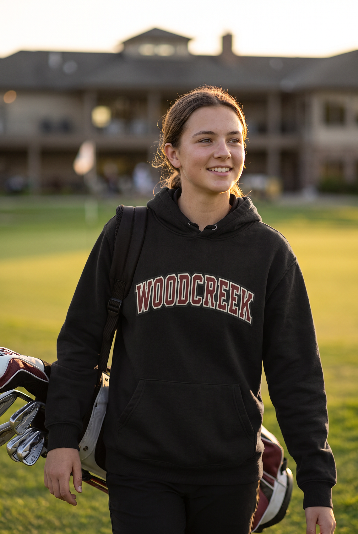 Woodcreek Girls Golf College Letter Fleece Hoodie in Black with arched Woodcreek lettering, worn walking off the 18th green
