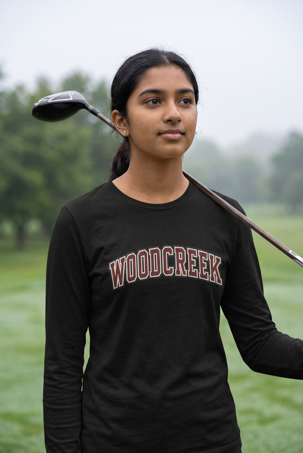 Woodcreek Girls Golf College Letter Long Sleeve Tee in Black with arched Woodcreek lettering, worn on the fairway