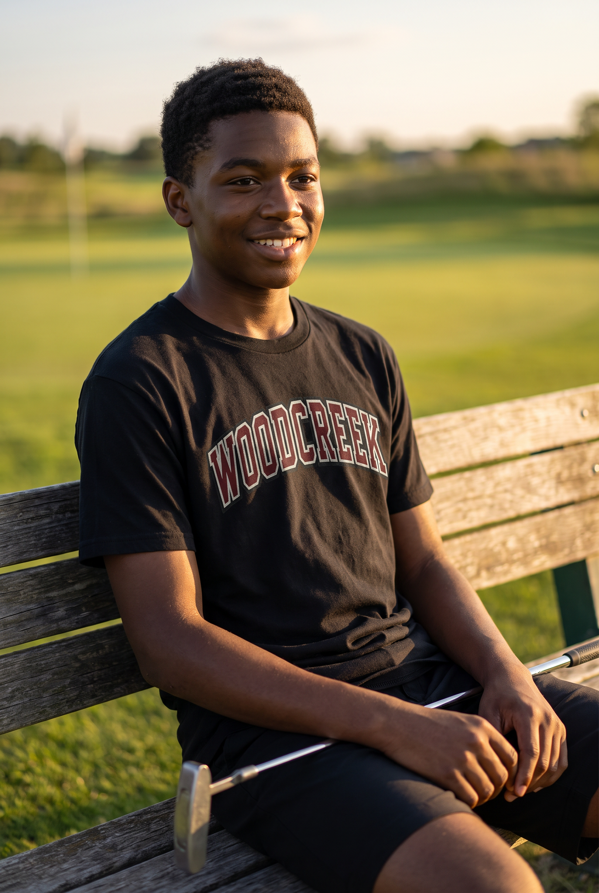 Woodcreek Boys Golf College Letter Value Tee in Black with arched Woodcreek lettering, worn by the putting green