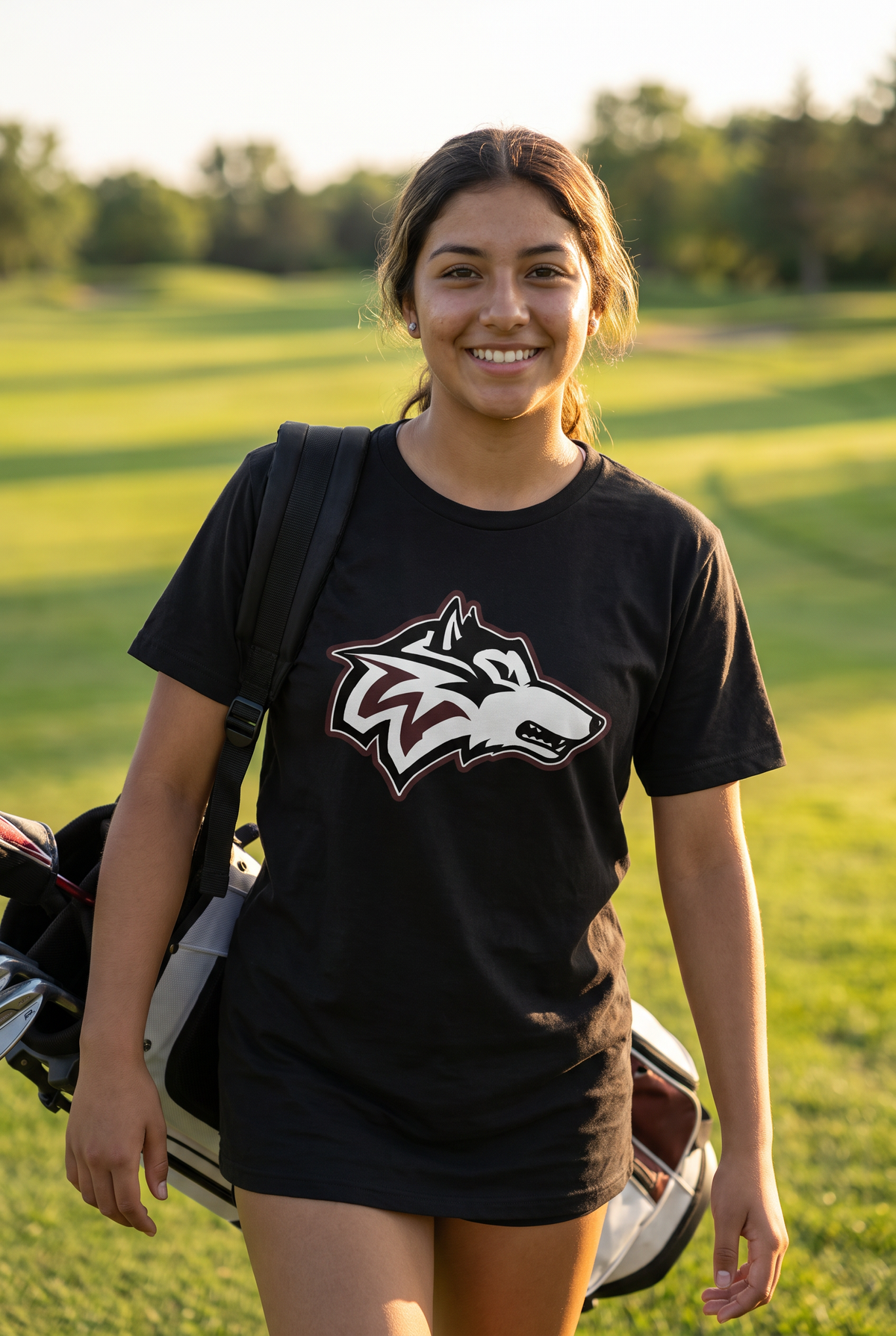 Woodcreek Girls Golf Value Tee in Black with the Woodcreek wolf head across the chest, worn walking the fairway