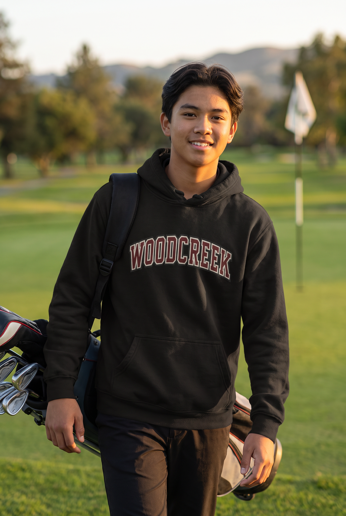 Woodcreek Boys Golf College Letter Fleece Hoodie in Black with arched Woodcreek lettering, worn walking off the 18th green