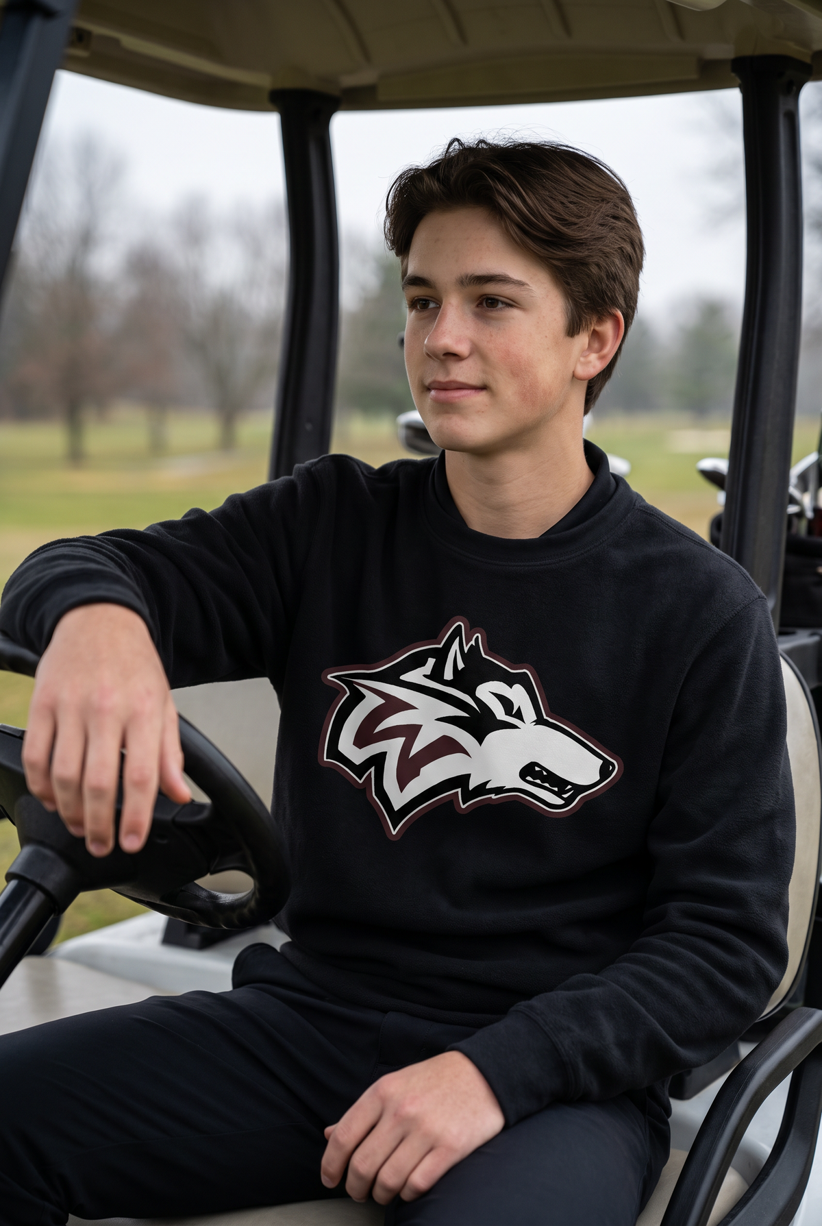 Woodcreek Boys Golf Fleece Crewneck in Black, second view on an overcast morning