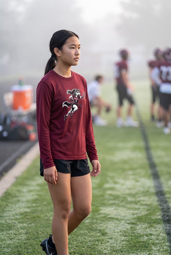Woodcreek Girls Flag Football Stiff Arm Long Sleeve Tee in Maroon, worn at a foggy morning practice